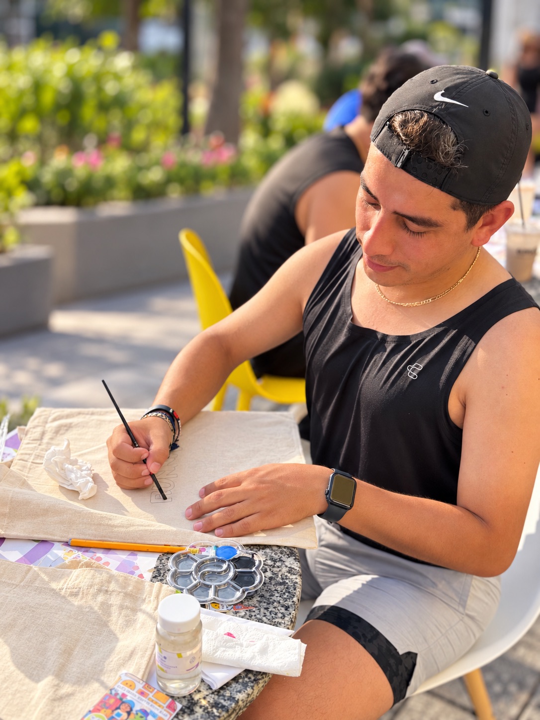 Joven pintando una tote bag en el área exterior de Art D'ler